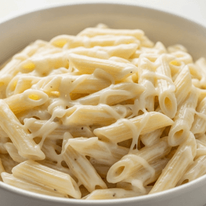 בתמונה קערת חרס עם פסטה ברוטב שמנת לבן מוקרם בגבינה צהובה בהירה מותכת